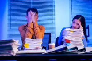 Stressed office workers in Singapore with heavy workload, highlighting heart attack risk and need for a heart specialist in Singapore.