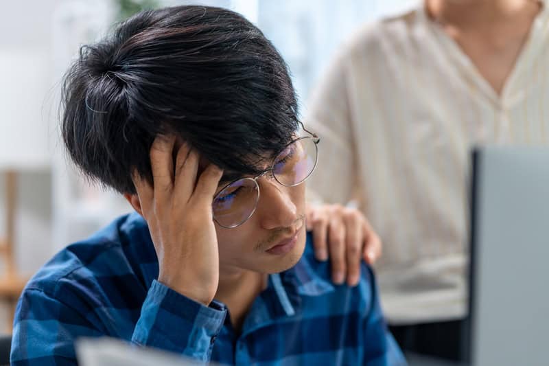 Stressed man holding his head, reflecting how emotional strain can impact heart health according to heart doctors in Singapore.