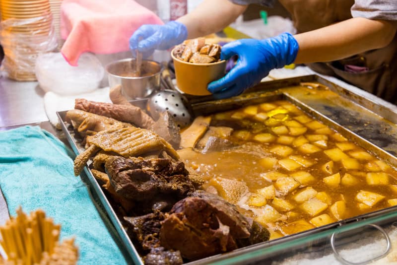 Serving hawker food in Singapore, showing dietary habits linked to heart attack risk and the need for a heart specialist in Singapore.