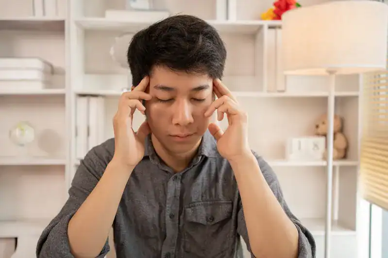 A man touching his temples and closing his eyes due to dizziness, illustrating unexpected heart disease symptoms that may require review by a Singapore cardiologist.