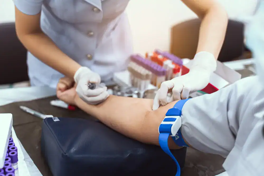 Cardiologist in Singapore performing a blood draw for cardiovascular screening and diagnostic testing in a clinical setting.