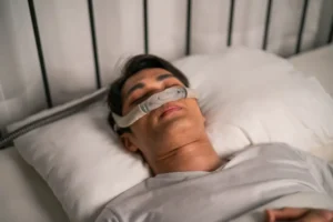 Man using a CPAP machine for sleep apnea to reduce risk of heart artery blockage
