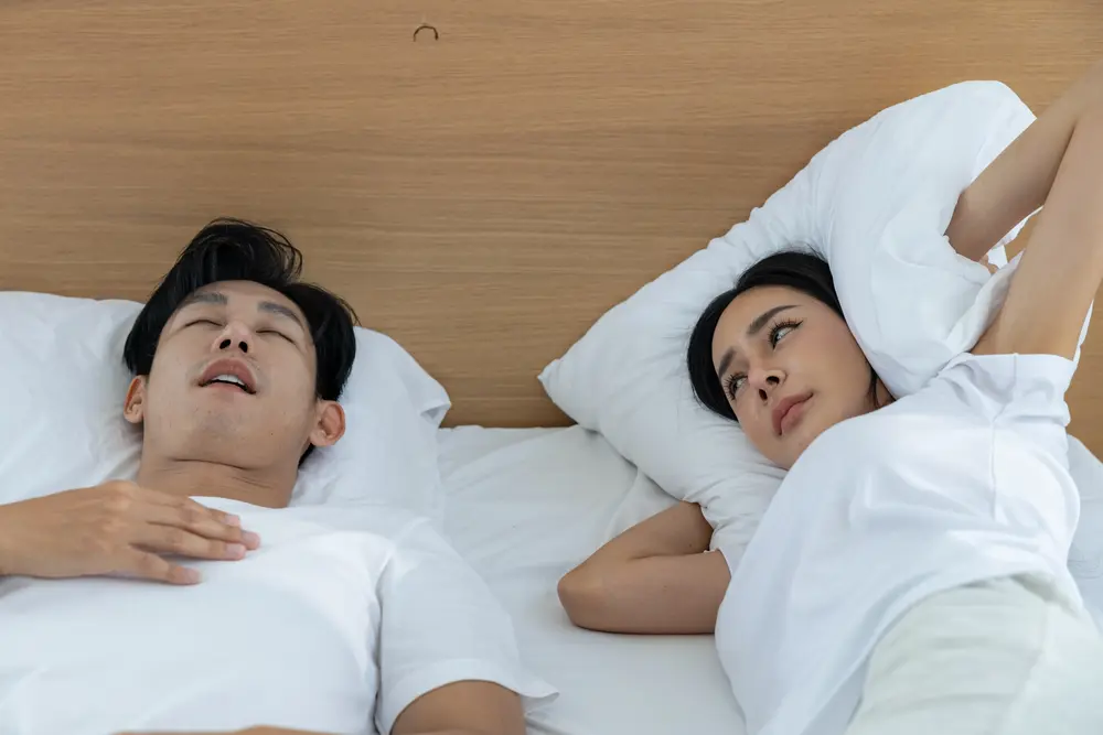 Man snoring during sleep while partner is awake, showing signs of sleep apnea