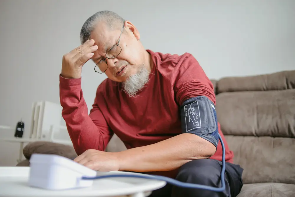 Man checking blood pressure at home feeling dizzy in hot weather