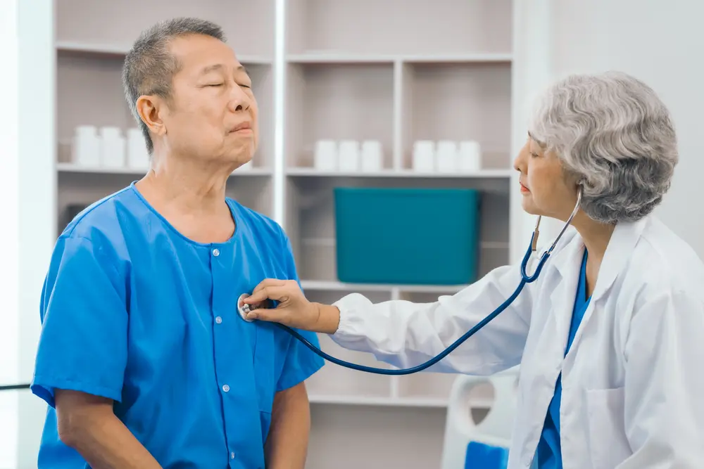 Doctor performing cardiovascular assessment on an elderly patient during evaluation for heart disease and coronary artery conditions in Singapore