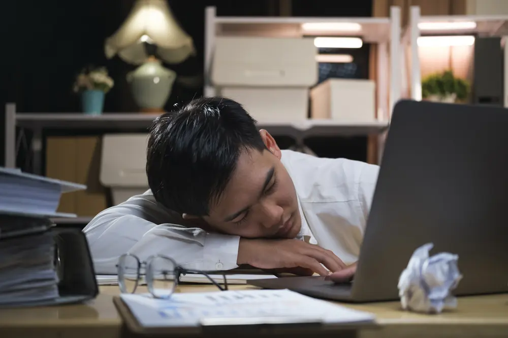 Person exhausted at work from lack of sleep, linked to heart disease risk